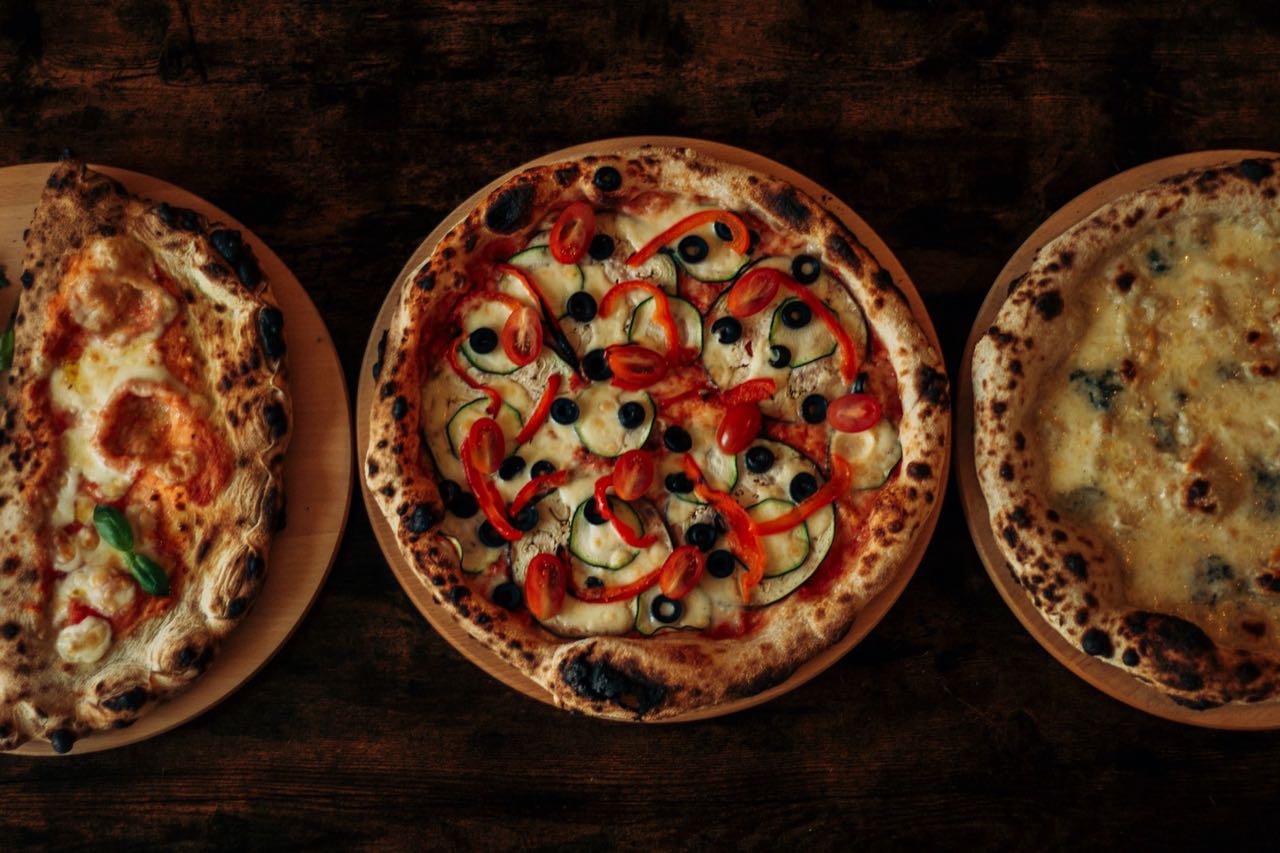 Drei frisch gebackene Pizzen auf Holzbrettern