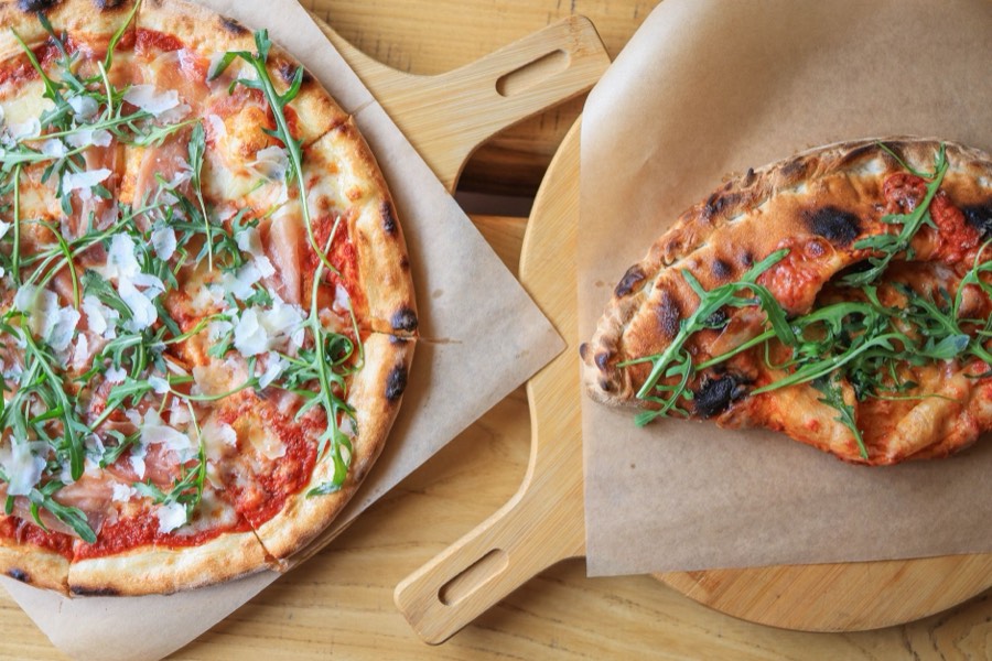 Pizza mit Schinken und Rucola auf Holzbrett